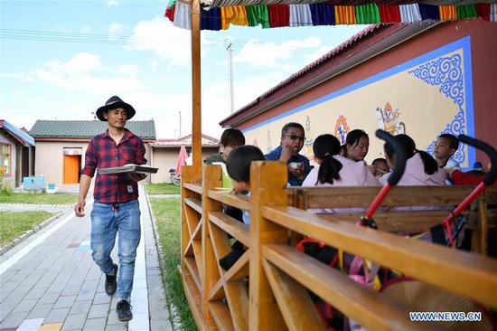 A villager serves dishes for guests in Gaxiu Village of Gahai Township, Luqu County, Gannan Tibetan Autonomous Prefecture, northwest China's Gansu Province, Aug. 13, 2019. In recent years, Gannan promoted culture and tourism industry to boost income of local people. (Xinhua/Chen Bin)